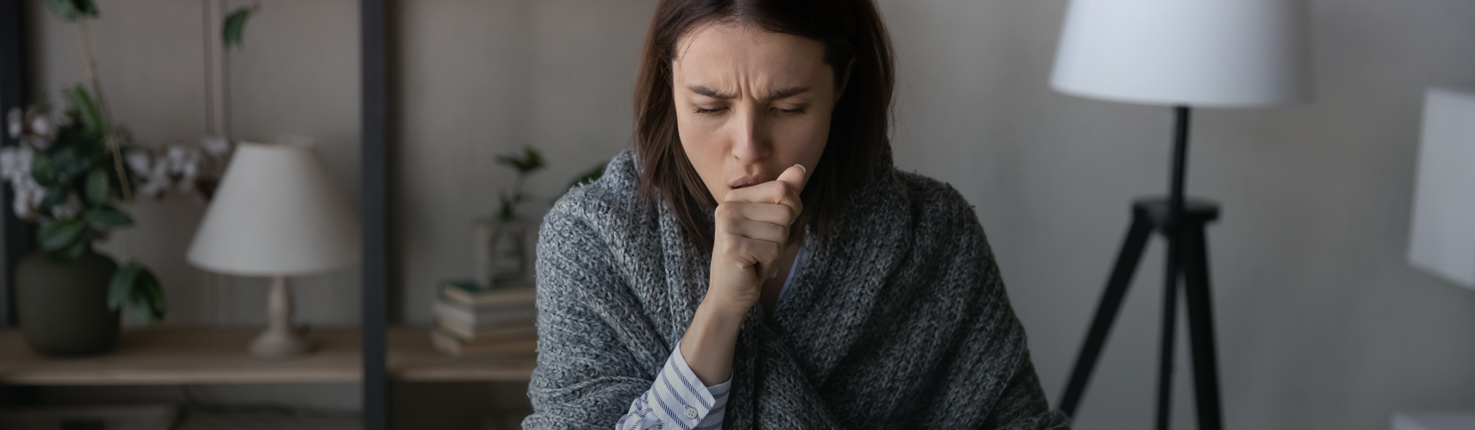 Persona adulta en la banca de un parque, tosiendo.