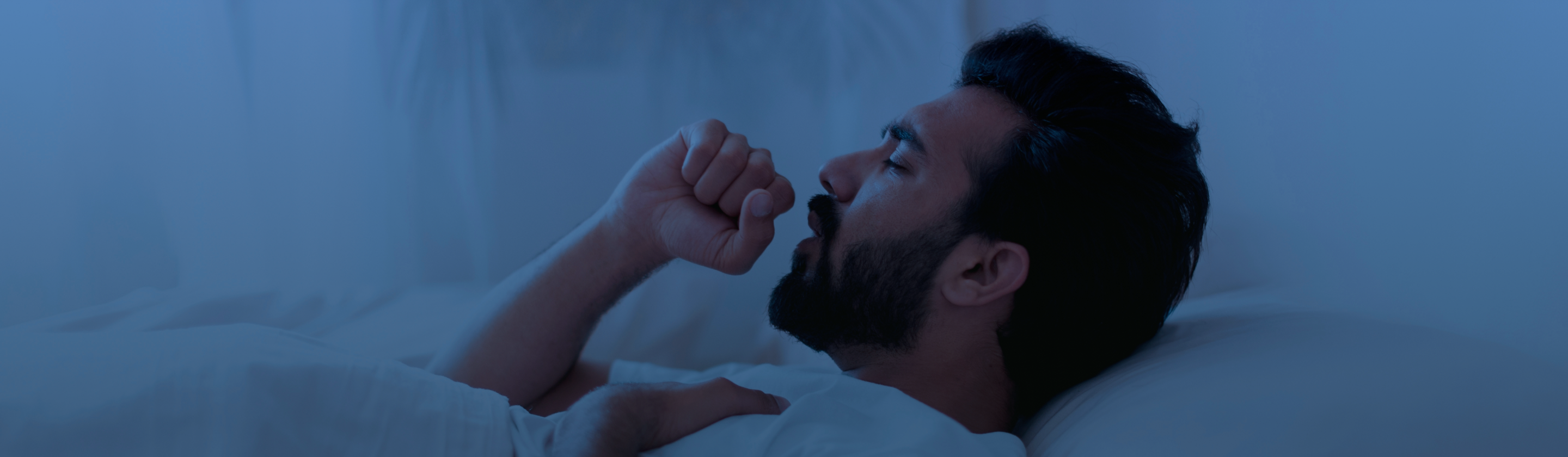 Persona adulta en la banca de un parque, tosiendo.