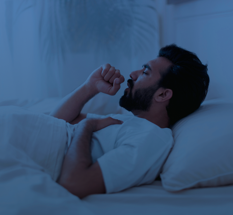 Persona adulta en la banca de un parque, tosiendo.